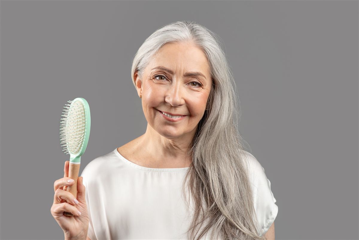 Lächelnde ältere Dame mit Haarbürste